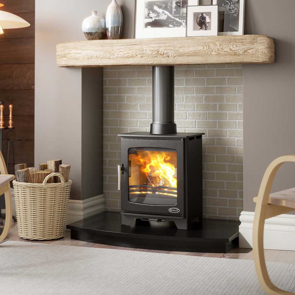 Hazelwood compact wood stove lit in a white brick closure