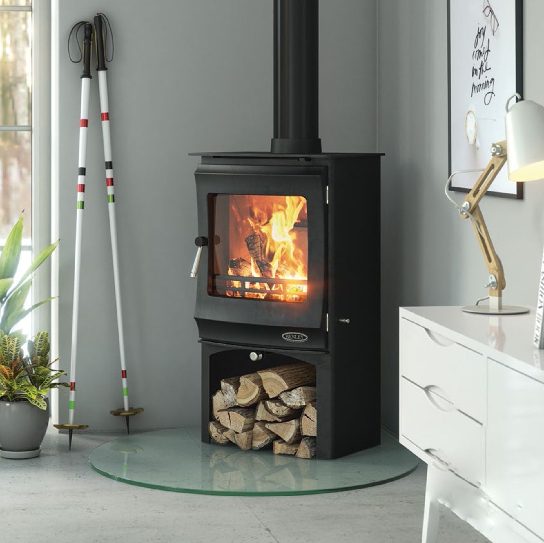 Elcombe wood burning stove lit with logbox on a glass base